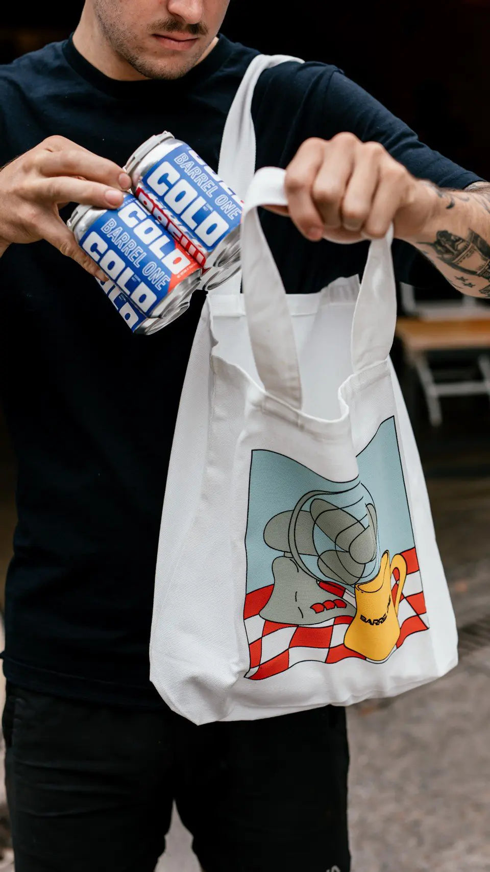 Barrel One’s stylish summer tote bag with a person using it to carry a 4 pack of cold brew coffee.
