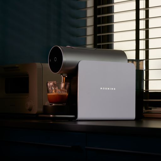 White Morning Coffee Machine with OLED screen displaying temperature setting via mobile app. Brewing using 'Breakfast Club' coffee capsules for a delicious morning cup. Upgrade your coffee game with the Morning Coffee Machine.